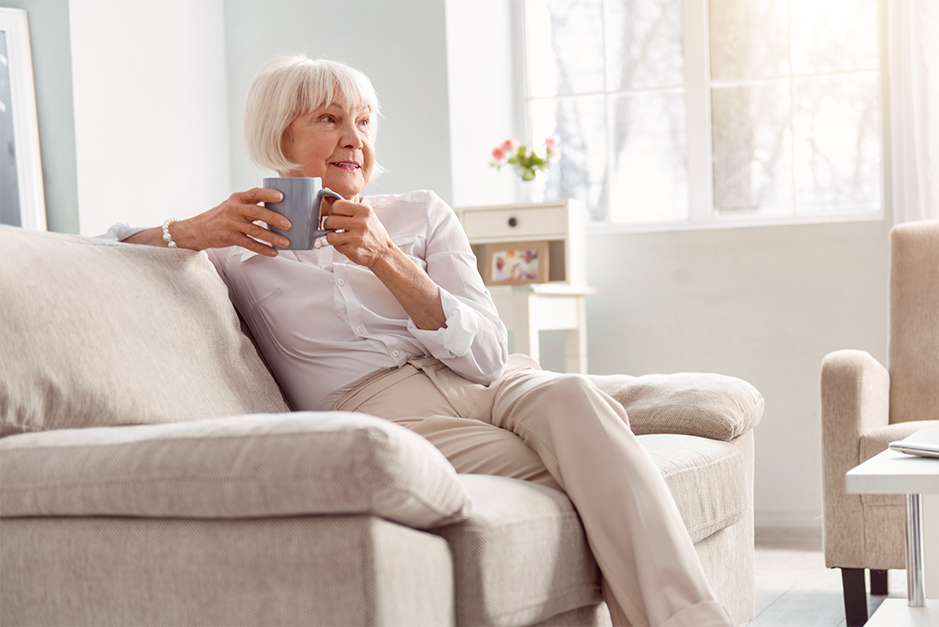 Senior woman sitting on couch drinking tea