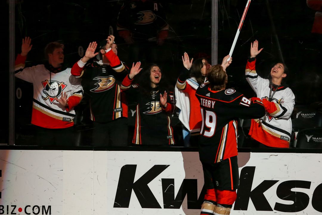 Troy Terry tosses a stick over the boards to an Anaheim Ducks fan