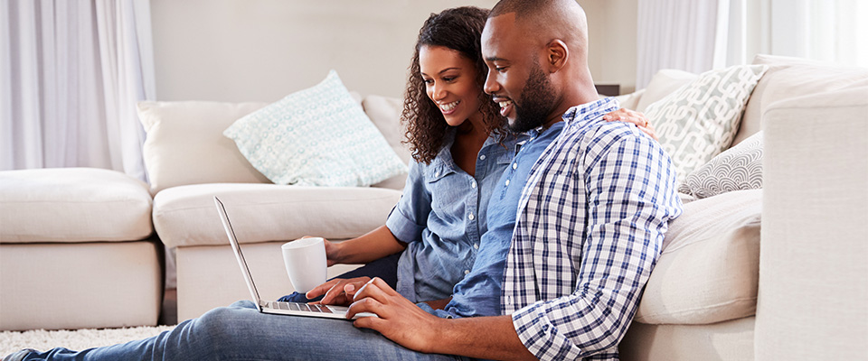A man and woman on a laptop in their living room