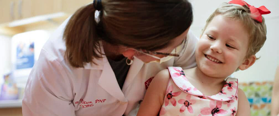 A girl sitting in a hospital bed while smiling at Phoneix Childrens