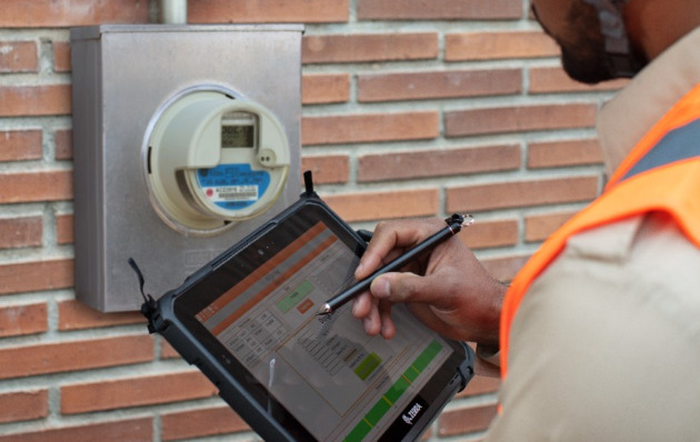 Worker outside checking a meter and making notes on his tablet