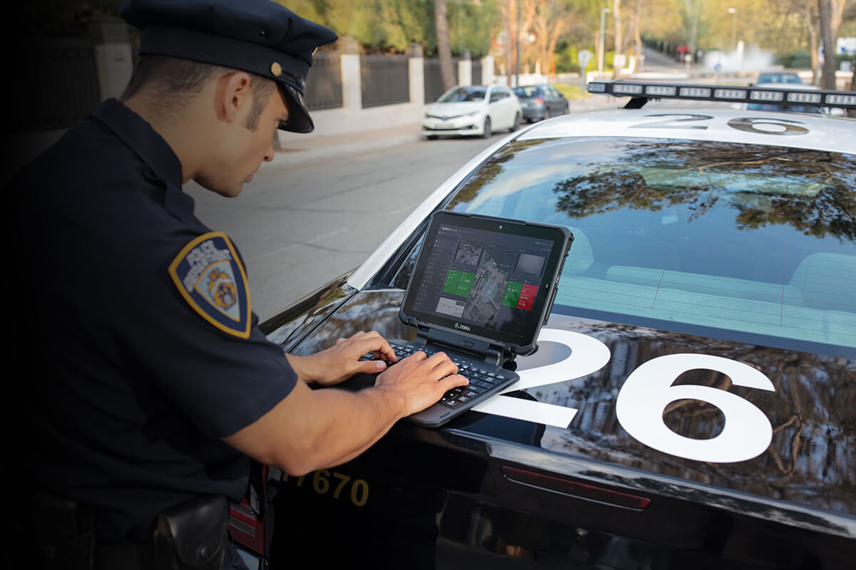 Police officer using Zebra's Rugged Tablet on the back of his squad car